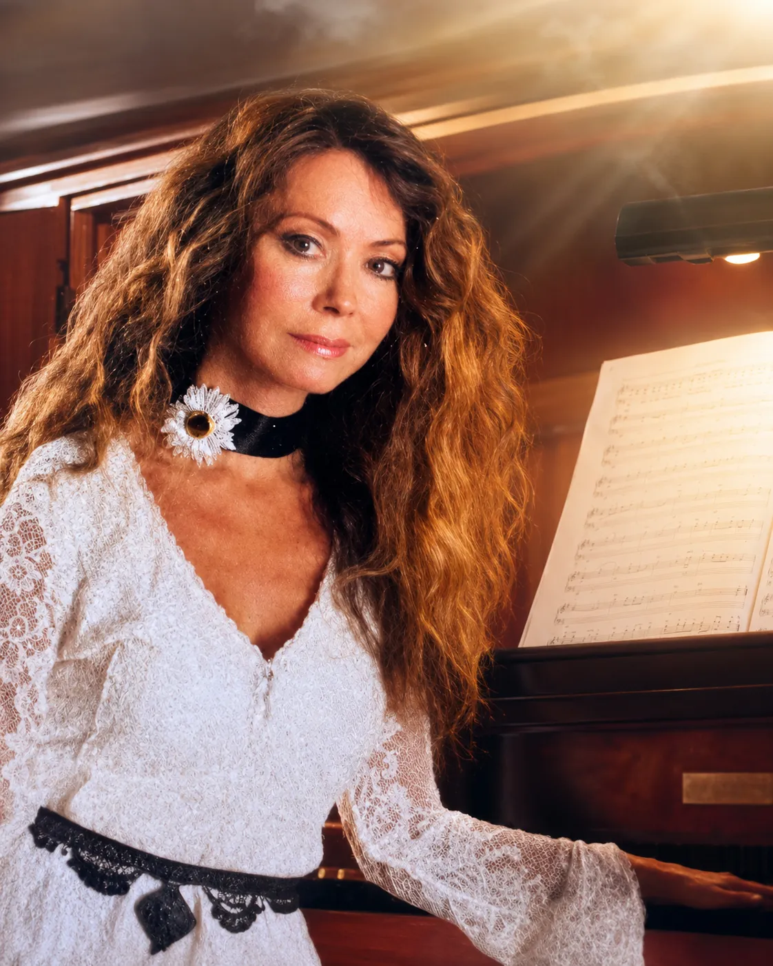 Dr. Marsha Long in a white dress seated at the piano, portrait in San Diego